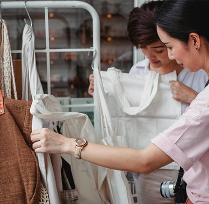 Dos personas comprando productos de tela reutilizable en una tienda, simbolizando el compromiso con la sostenibilidad y la responsabilidad social en el marketing.